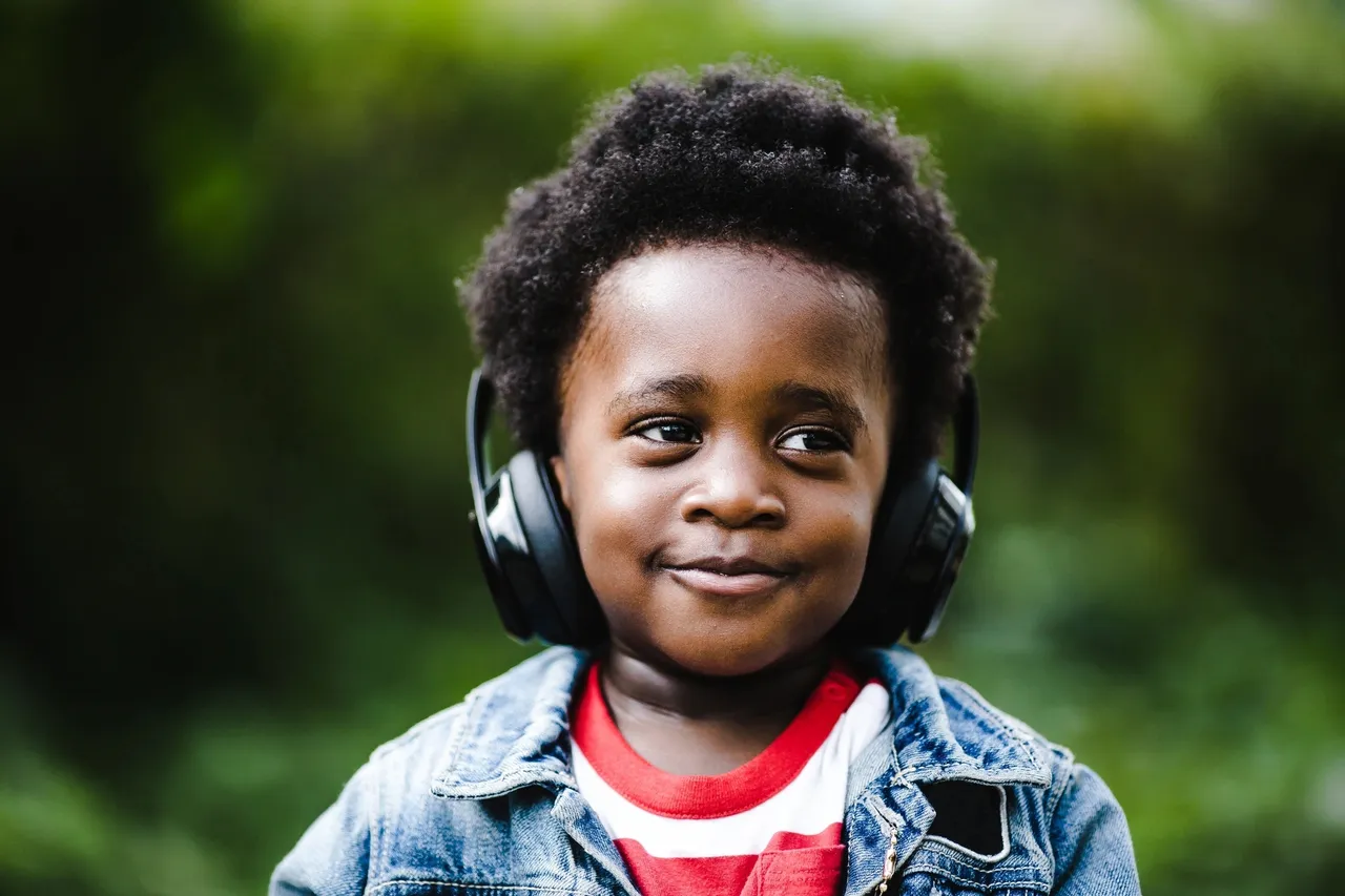 A young boy wearing headphones and smiling for the camera.