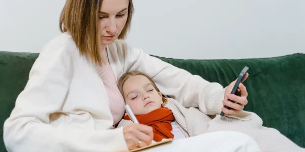 A woman is writing on paper with her child.