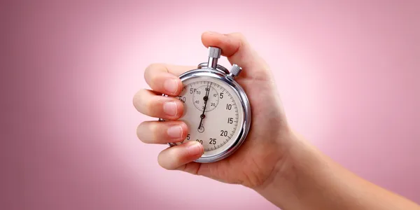 A person holding an analog stopwatch in their hand.