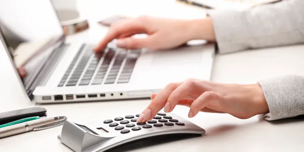 A person using a laptop and keyboard on a desk.