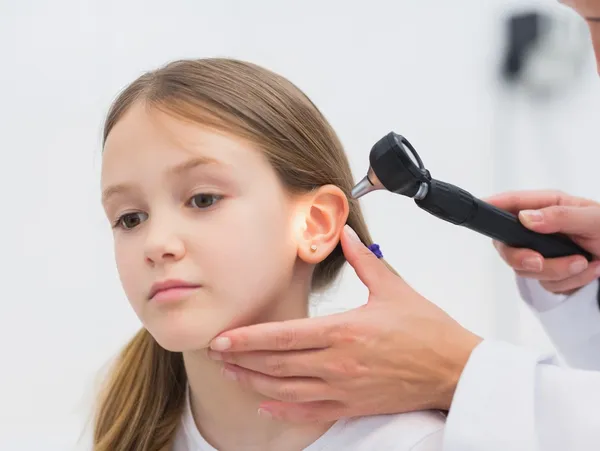 A woman is getting her ear examined by an audiologist.