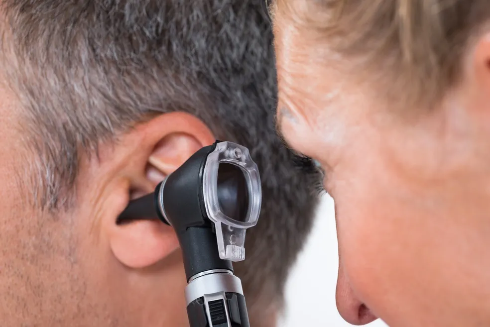 A man is getting his ear examined by an audiologist.