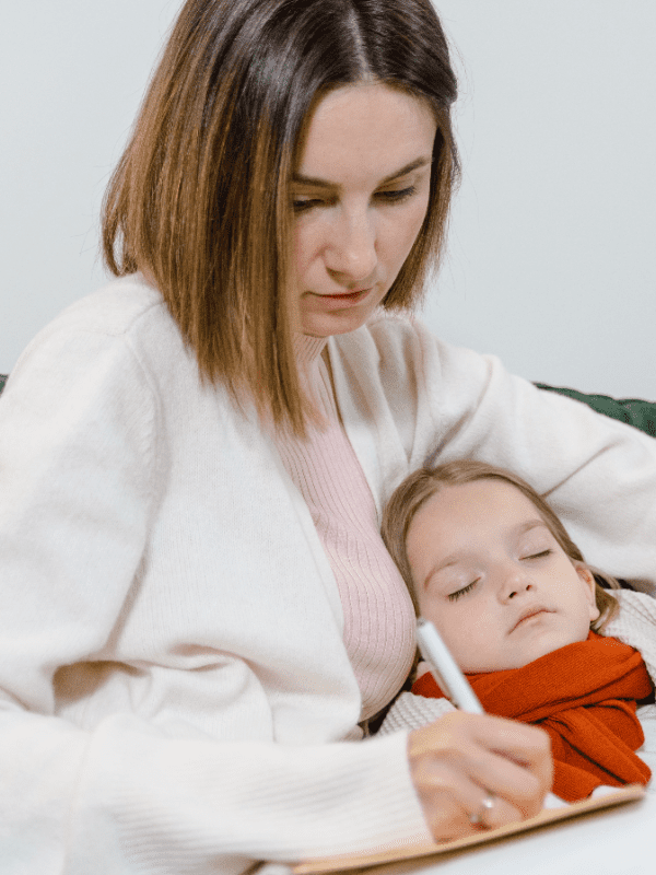 A woman is holding a child and using a thermometer.