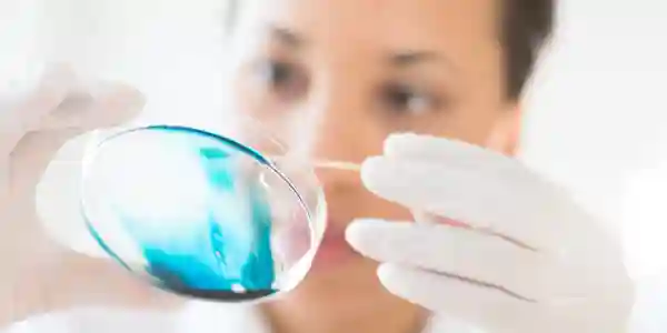 A woman is looking at the glass with a needle.