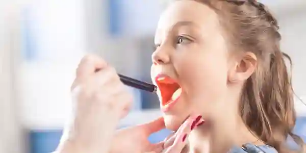 A child is being held up to brush his teeth.