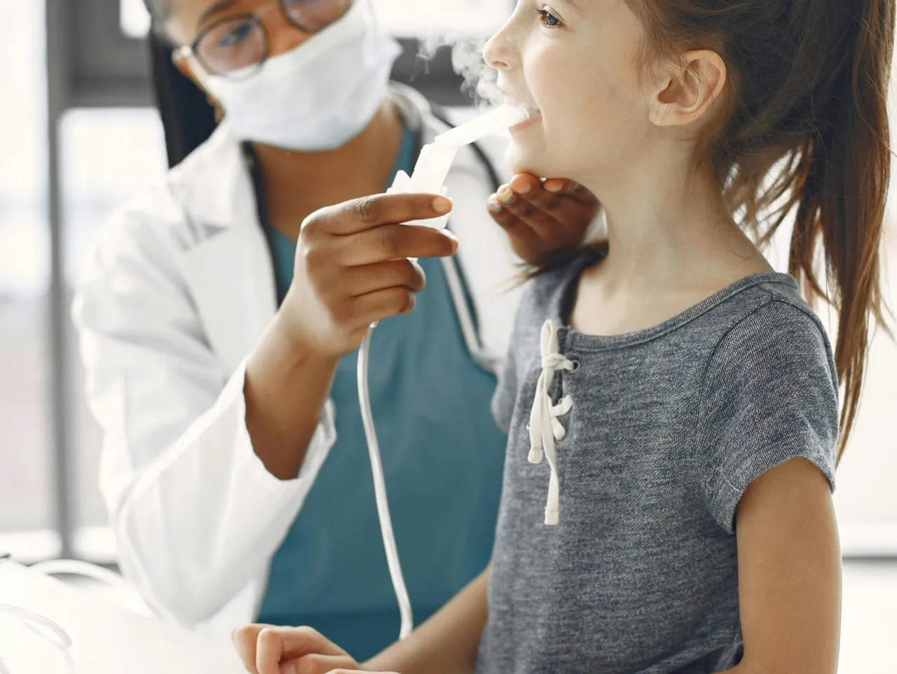 A doctor is examining the teeth of a young girl.