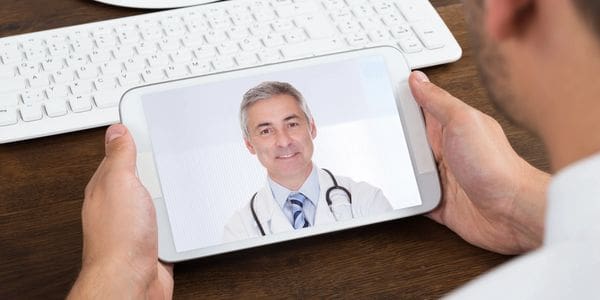 A person is holding up a tablet with a picture of a doctor on it.