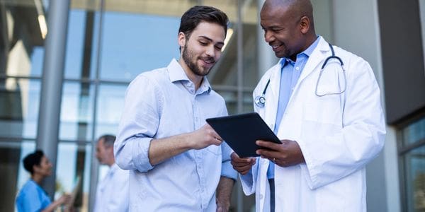 Two doctors are looking at a tablet.