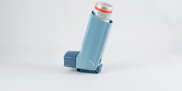 A blue asthma inhaler is sitting on the floor.