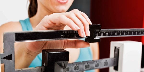 A woman is standing on the scale and measuring her weight.