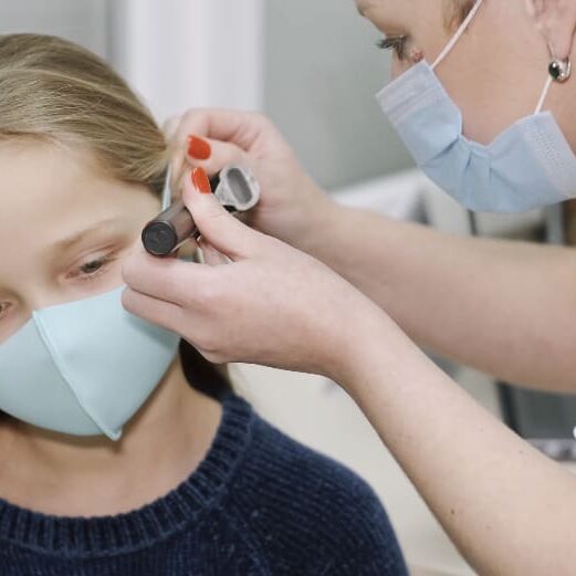 A woman wearing a mask is putting on an ear piece.