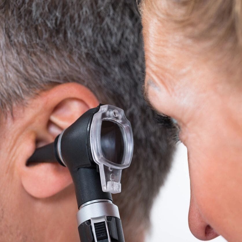 A man is getting his ear examined by an audiologist.