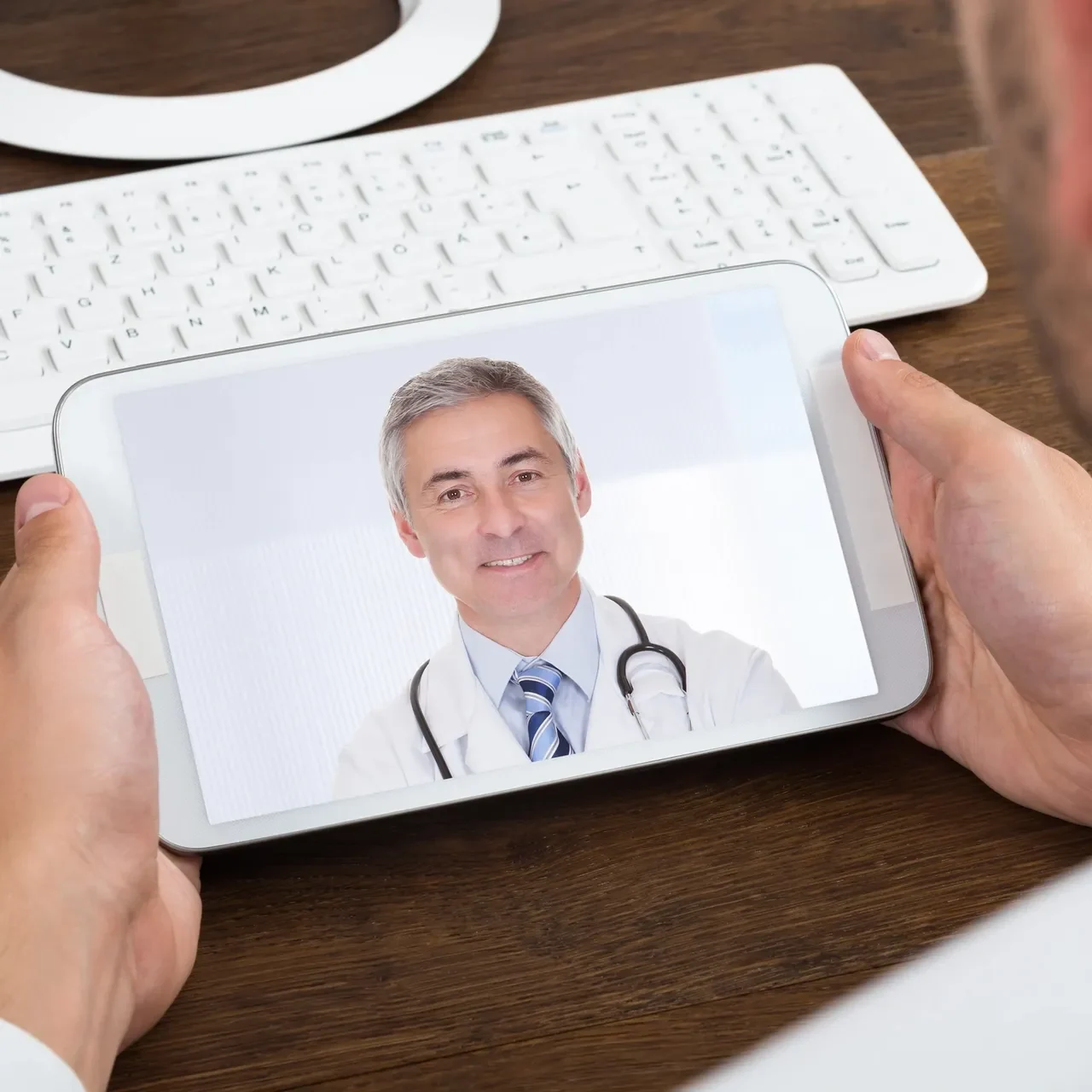 A person holding up a tablet with a picture of a doctor on it.